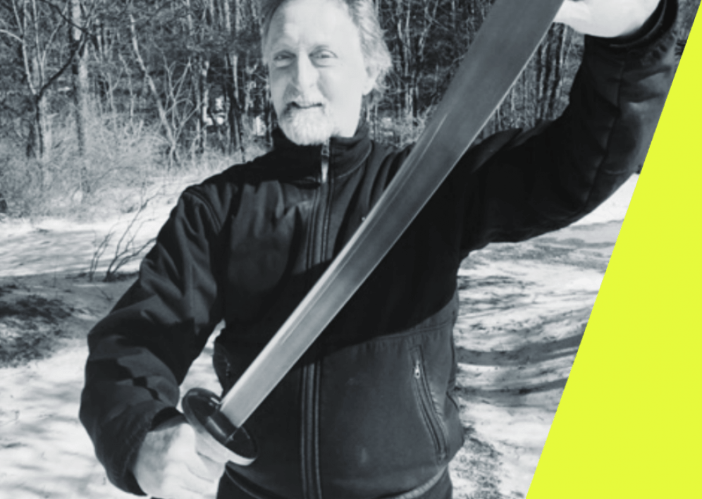 Backstage Studio: Greg DiLisio in a forest clearing holding a sword